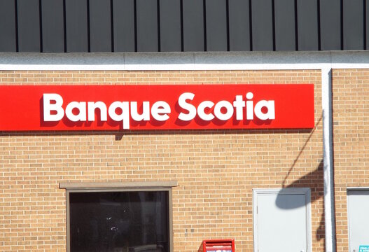 Gatineau, Quebec, Canada &ndash; April 18, 2026: A red sign with white lettering for "Banque Scotia" is mounted on a tan brick wall above a glass window on Boulevard Saint-Joseph.
