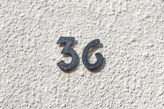 house number 36 at the white structured plaster wall