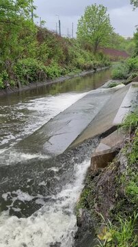 Massive urban wastewater discharge flowing from municipal treatment plant pipes into a polluted water canal.