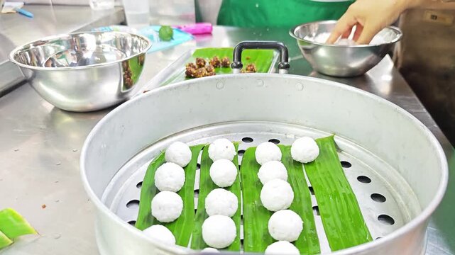 Arranging raw tapioca balls on banana leaf inside a steaming pot.