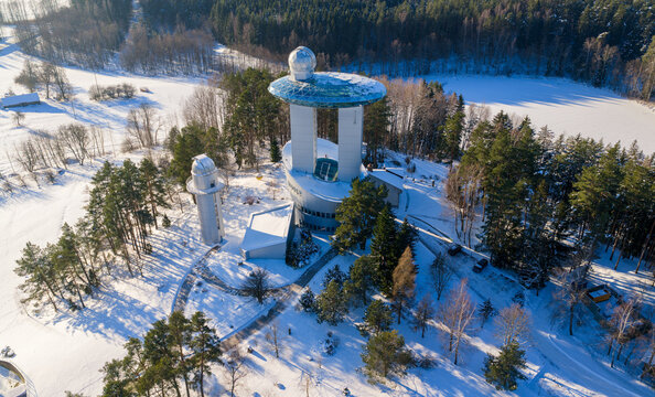 Aerial view of the Lithuanian Museum of Ethnocosmology with its futuristic architecture and glass deck surrounded by snow-covered trees in Kulionys, Utenos apskritis, Lithuania.