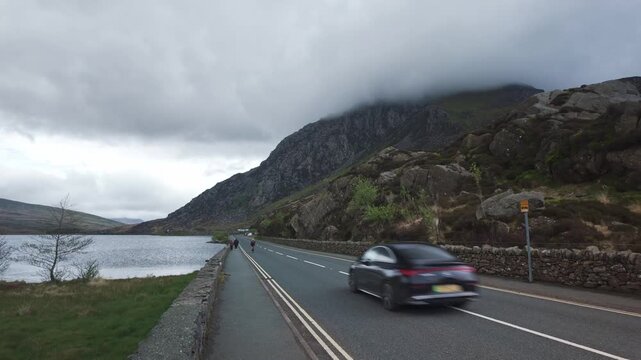 Cyclist and Traffic on the A5 Road Passing Llyn Ogwen, Eryri (Snowdonia), North Wales