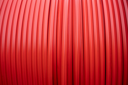 Red electrical cable conduit winding on a reel