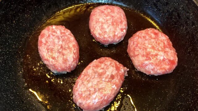 Raw minced meat patties placed on a frying pan with oil
