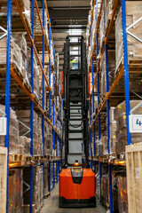 Warehouse management system featuring high-density pallet racking and storage solutions in a modern distribution centre. A very narrow aisle (VNA) or articulated forklift truck is operating on site © Val
