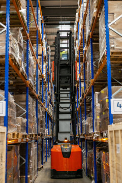 Warehouse management system featuring high-density pallet racking and storage solutions in a modern distribution centre. A very narrow aisle (VNA) or articulated forklift truck is operating on site