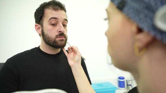 Cosmetologist preparing male patient for filler injection