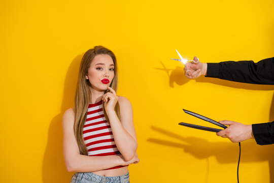 Fashionable young woman with long blonde hair thoughtfully posing wearing red striped top against vibrant yellow background