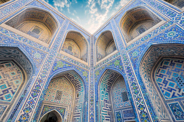 Obraz premium UZBEKISTAN - SAMARKAND - ULUGH BEG MADRASA, THE OLDEST OF THE THREE REGISTAN MADRASAS, WITH ISLAMIC ARCHITECTURE, MOSAIC TILES AND ARABIC CALLIGRAPHY IN HISTORIC UZBEKISTAN