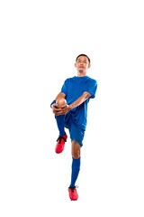 Fototapeta premium Professional Indonesian southeast asian soccer player in blue uniform performing a knee-to-chest leg stretch, isolated on a white background. Ideal for fitness and sports marketing