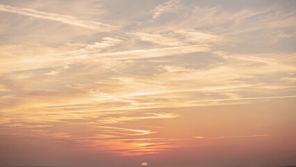 Fototapeta premium Soft golden sunset sky with delicate cirrus clouds stretching across a clear horizon