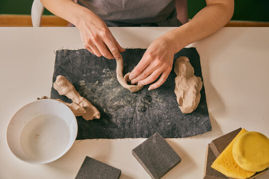 Close up view of female hands modeling clay coil on workshop table for ceramic craft