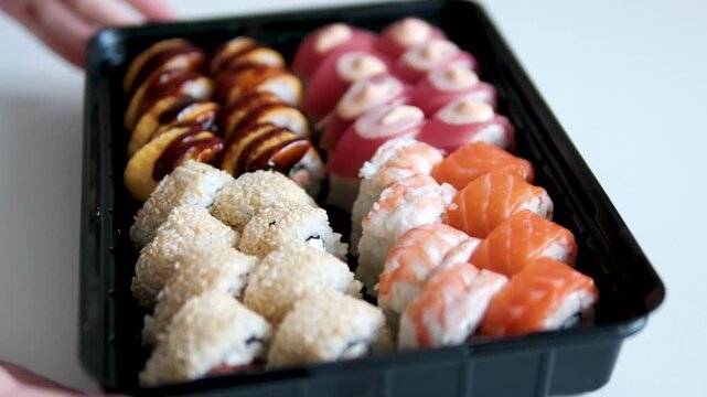 Assorted sushi platter with various types of nigiri, maki rolls, and sashimi on black plate, showcasing Japanese cuisine. Authentic Japanese Food and Culinary Arts.