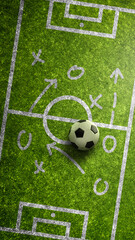 Fototapeta premium Vertical top view of a classic soccer ball on a green grass pitch with white tactical game plan markings and arrows for sports strategy