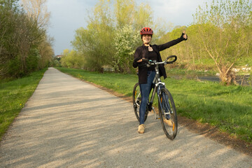 Obraz premium Happy woman cyclist showing thumbs up gesture while riding