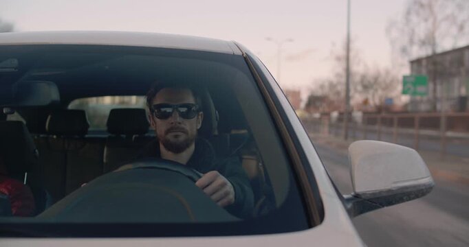 A handsome young man drives a car in a city center in Europe
