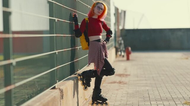 Stylish young woman with pink hair posing on rollerblades