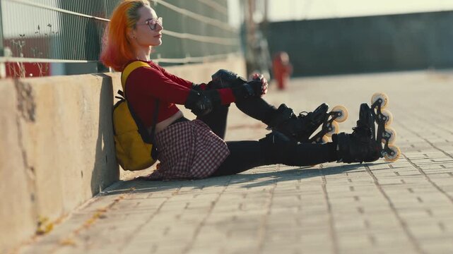 Young woman with pink hair resting after rollerskating