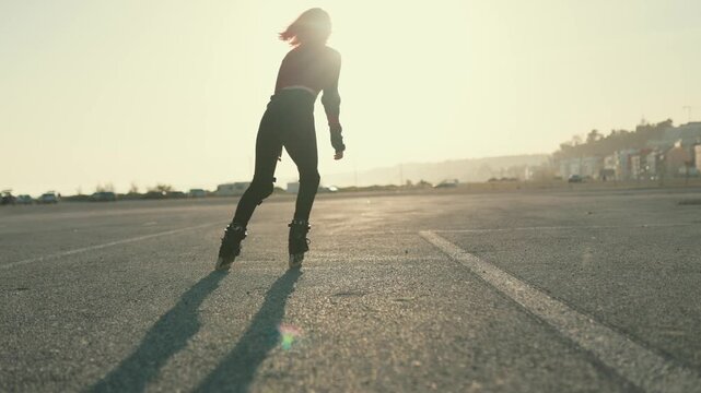 Silhouette of a woman rollerblading at sunset