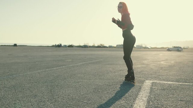 Young woman rollerblading on asphalt during sunset