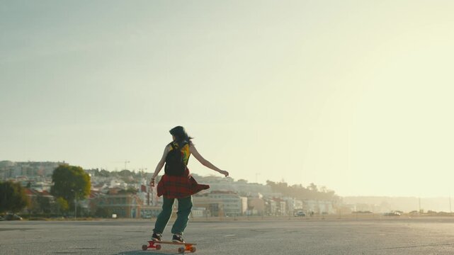 Young stylish skater girl riding a longboard at sunset