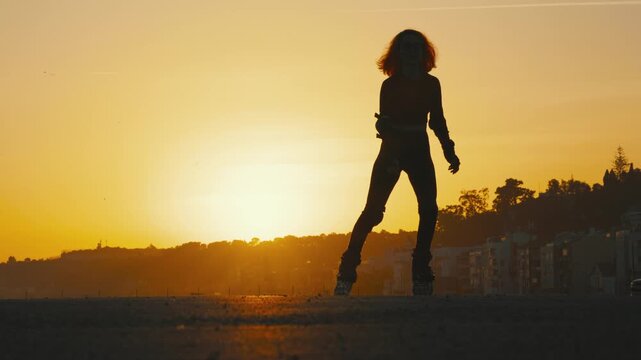 Silhouette of a woman roller skating during sunset