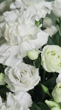 Vertical 4K macro of white eustoma bouquet. Close-up of fresh lisianthus flowers, carnations, and chrysanthemums with green buds.