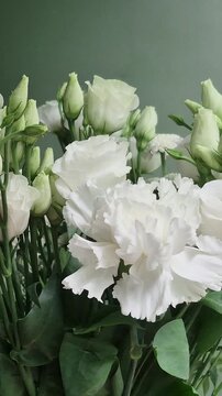 Vertical 4K macro of white eustoma bouquet. Close-up of fresh lisianthus flowers, carnations, and chrysanthemums with green buds.