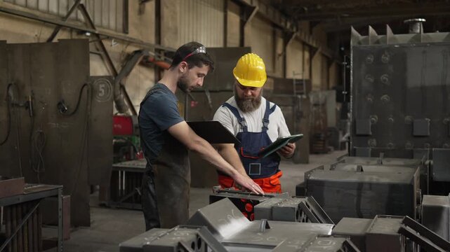 Industrial workers discussing project plans in a metal factory