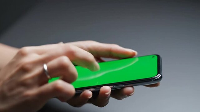 Close up view of hands interacting with smartphone green screen mockup device