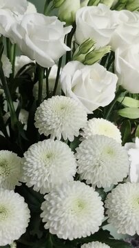 Vertical 4K macro of white eustoma bouquet. Close-up of fresh lisianthus flowers, carnations, and chrysanthemums with green buds.