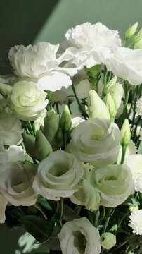 Vertical 4K macro of white eustoma bouquet. Close-up of fresh lisianthus flowers, carnations, and chrysanthemums with green buds.