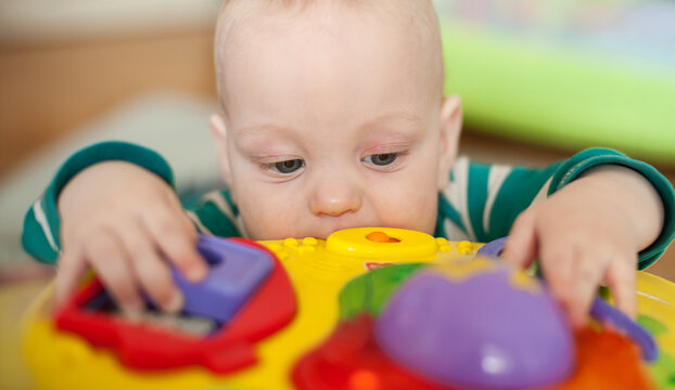 Curious infant marvels at a vibrant yellow activity toy, tiny fingers and exploring mouth finding endless delight during daytime play