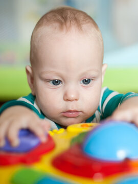 Gentle baby hands reach out to touch and feel the colorful buttons of an engaging learning toy. The infant's concentrated expression shows deep curiosity and joy during discovery play indoors