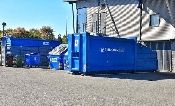 A modern waste management system: a blue Europress compactor collecting and compacting waste and cardboard in an open area.