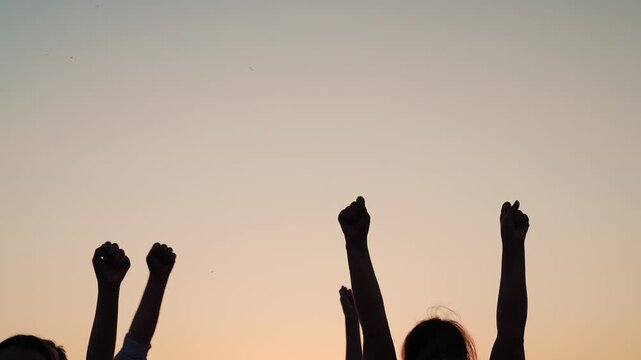 Business team unity partners. Teamwork. Group people against sky raise their fists. Voluntary voting, expressing consent, supporting freedom. People raise their hands together, voting with their fists