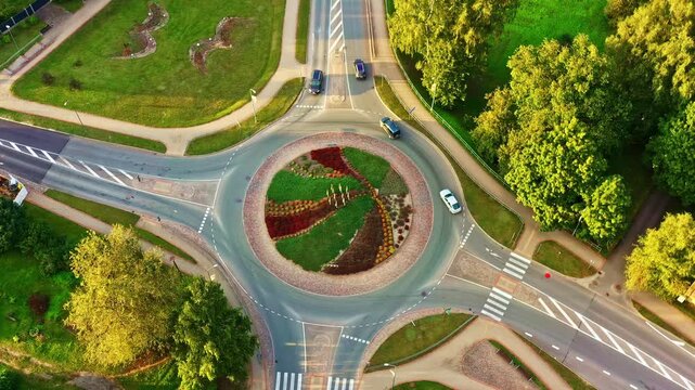Truck transporting logs drive on roundabout on sunny summer evening, aerial top view