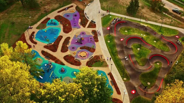 Modern activity complex featuring children's playground and pump track in summer, aerial view in golden hour sunlight
