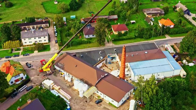 Dairy plant modernization with a mobile crane lifting construction materials, aerial parallax shot