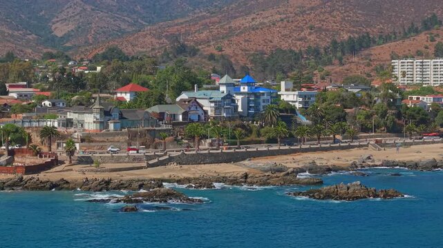 A telephoto flyover of the boardwalk along the shore of Playa Chica in Papudo, Chile, on a morning with a light mist