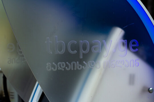 Tbilisi, Georgia - May 12, 2026: Horizontal street photo close up. TBC Bank logo on plastic wall of ATM machine. GEL bill, lari. Concept of salary, credit, budget, cash money, loan, debt, pay tax