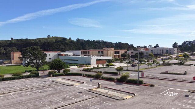 Aerial view of the nearly deserted Skyline College campus and empty parking lot on a sunny day in San Bruno, California, showing the stillness of academic grounds during a break
