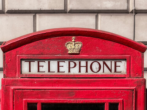 Red British Telephone Box Close-Up With Crown Emblem and Weathered Paint Texture
