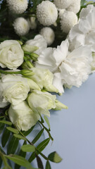 Fototapeta premium Vertical photo of fresh white flower bouquet with Eustoma and Chrysanthemums on light blue background.