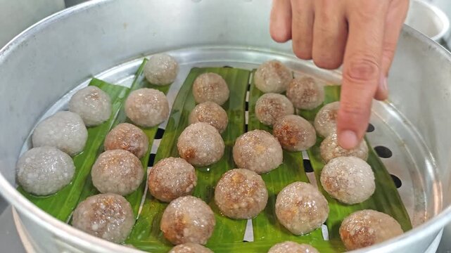 Steamed translucent sago balls on banana leaves inside an aluminum steamer.