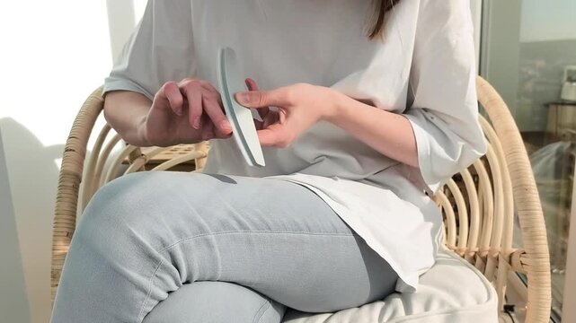 Home manicure routine shows nail treatment using buffer and file tools. Female performs selfcare process shaping fingernails carefully. Beauty concept reflects hygiene and grooming indoors..