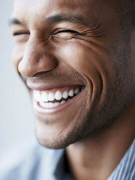 Black man laughing heartily with a bright, genuine smile and white teeth.