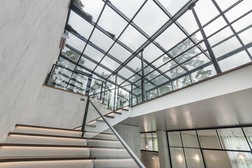 Fototapeta premium Magnificent design of the lobby in a luxurious mansion. Glass roof, stairs with lighting. Loft style.
