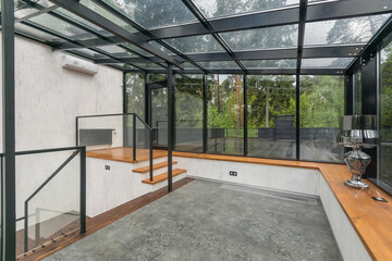 Obraz premium Luxury glazed terrace in a private mansion. Loft-style decoration. Magnificent natural landscape outside the window.
