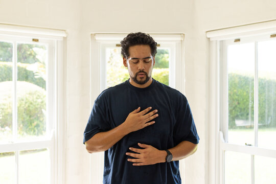 African American man standing between three windows doing breathwork with navy tee watch